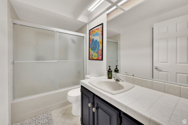 Full bath with toilet, vanity, tile patterned floors, and shower / bath combination with glass door | Image 34