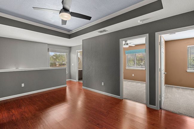 Unfurnished room featuring a ceiling fan, wood finished floors, a textured ceiling, a smoke detector, and crown molding | Image 18