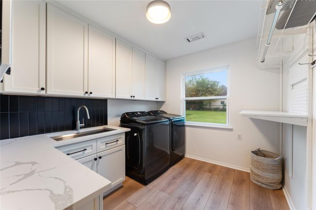 The utility room features custom-built cabinets and a large sink, perfect for storage! | Image 20