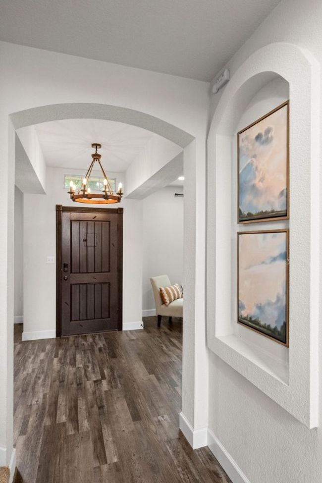 Entrance foyer with a chandelier, dark wood-style floors, baseboards, and arched walkways | Image 17