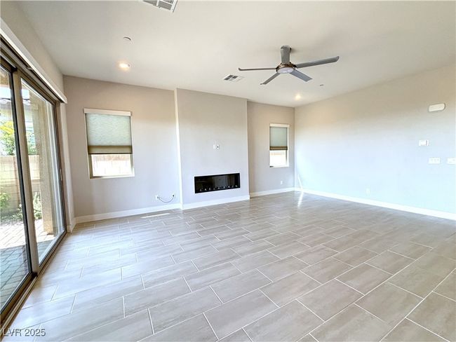 Unfurnished living room featuring recessed lighting, ceiling fan, a glass covered fireplace, baseboards, and visible vents | Image 7