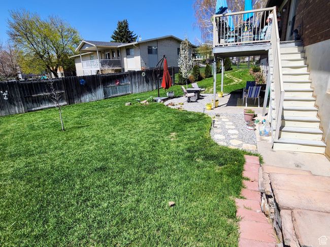 View of yard featuring a deck, fence, a patio, a fire pit, and stairs | Image 47