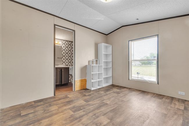 Spare room with wood finished floors, vaulted ceiling, a textured ceiling, and ornamental molding | Image 9