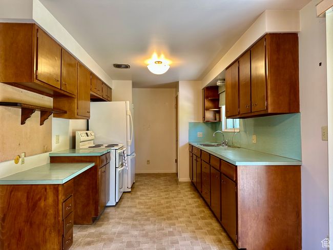 Kitchen of functionable design with white electric range, open shelves, light countertops, brown cabinets, and backsplash | Image 5