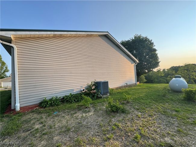 Property exterior at dusk featuring central air condition unit and a lawn | Image 39
