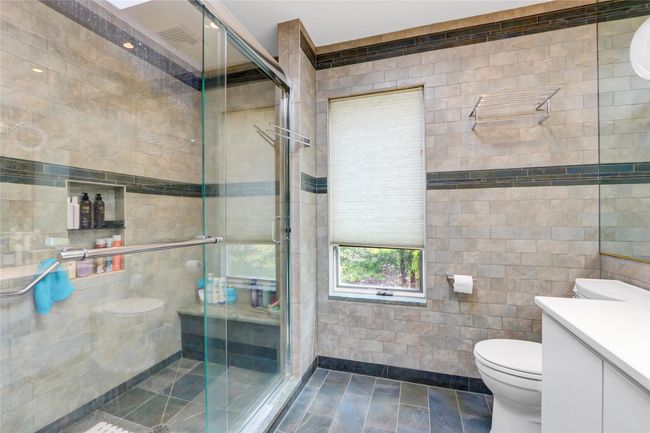 Full bathroom with tile walls, a shower stall, toilet, and vanity | Image 15