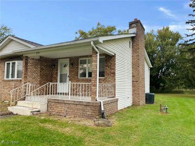 Ranch-style home featuring a porch, a front lawn, and a garage | Image 1