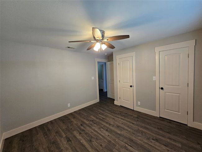 Unfurnished bedroom with dark wood-style floors and ceiling fan | Image 9