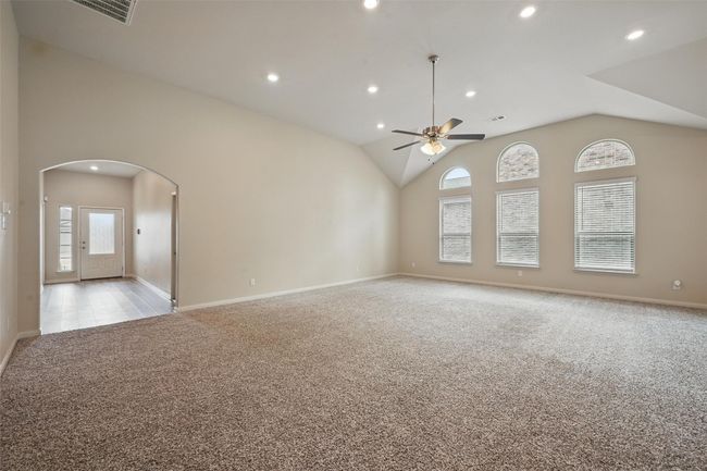 Unfurnished living room with light carpet, arched walkways, recessed lighting, and a healthy amount of sunlight | Image 6