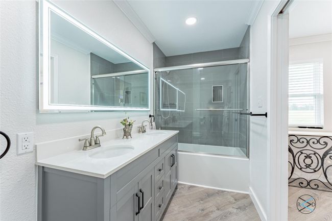 Bathroom with hardwood / wood-style flooring, combined bath / shower with glass door, ornamental molding, and vanity | Image 17