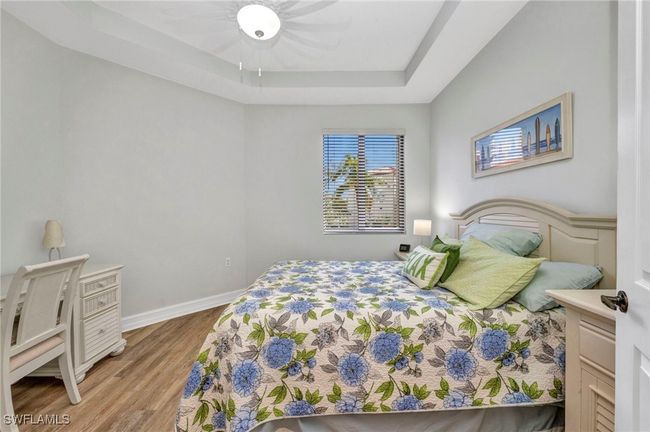 Bedroom with a tray ceiling, wood finished floors, and ceiling fan | Image 25