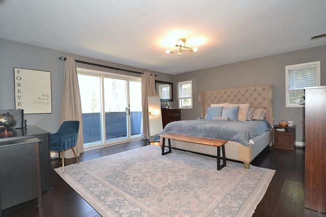 Bedroom with dark wood-style floors, access to outside, and visible vents | Image 17