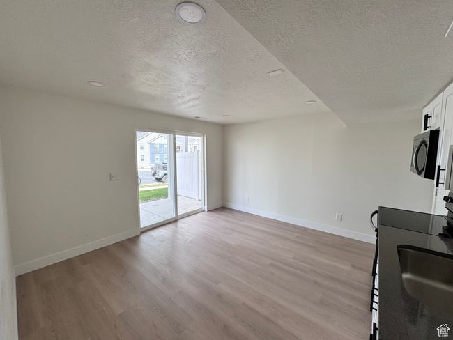 Interior space with light wood-style floors, baseboards, a textured ceiling, and stainless steel microwave | Image 31