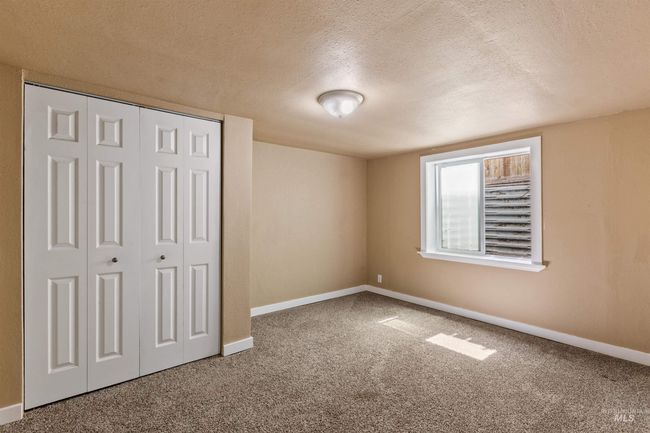 Unfurnished bedroom with a textured ceiling, carpet flooring, and a closet | Image 34