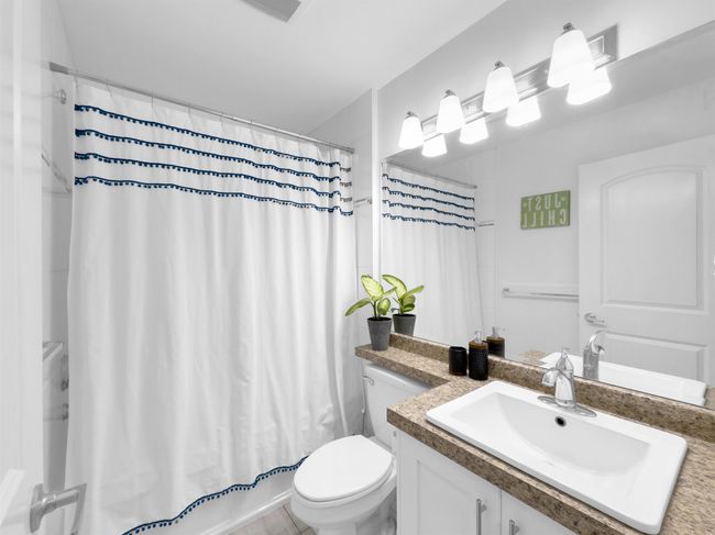 Bathroom with toilet, vanity, and shower / bathtub combination with curtain | Image 18