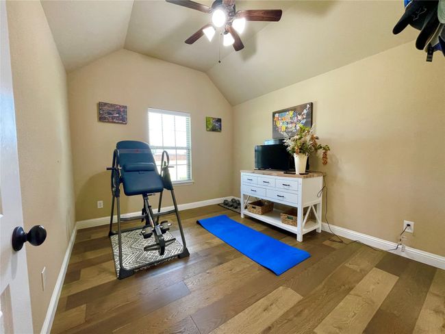 Workout area with ceiling fan, vaulted ceiling, wood finished floors, and baseboards | Image 28
