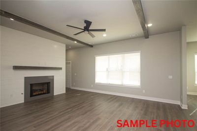 SAMPLE PHOTO: The centerpiece of the living area is a cozy fireplace framed by shiplap surround and a wood mantel, while ample windows flood the space with natural light. | Image 2