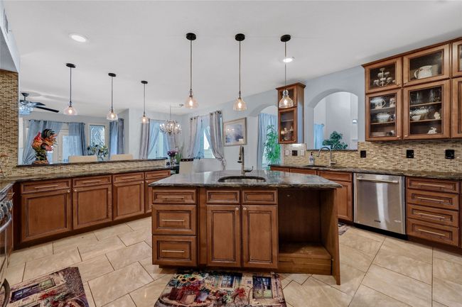 Kitchen featuring kitchen peninsula, decorative light fixtures, stainless steel appliances, and sink | Image 12