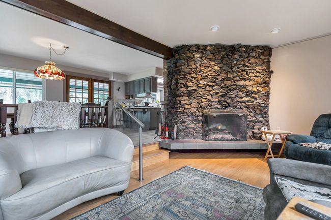 Living room featuring light wood finished floors, beamed ceiling, and a fireplace | Image 15