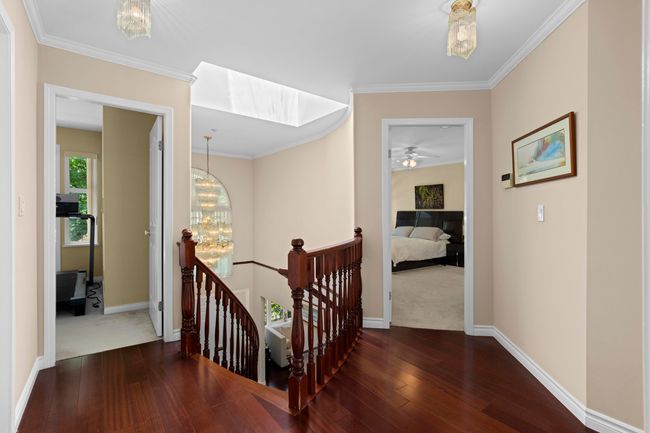 Corridor with an upstairs landing, hardwood / wood-style flooring, a chandelier, and ornamental molding | Image 15