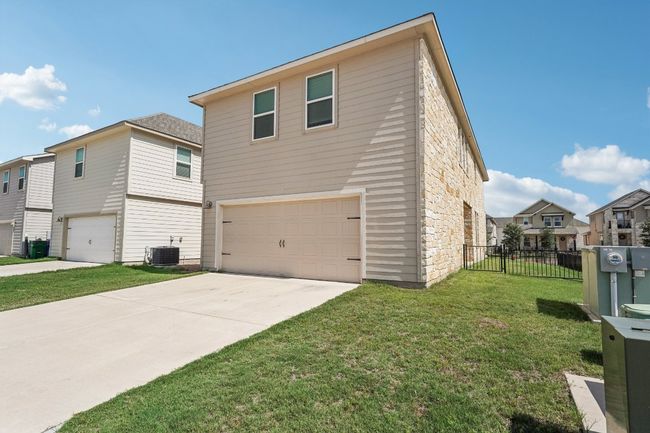 View of property exterior with an attached garage, stone siding, central AC unit, and concrete driveway | Image 22