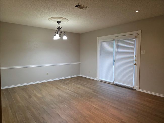 Spare room featuring a chandelier, wood finished floors, baseboards, and a textured ceiling | Image 10