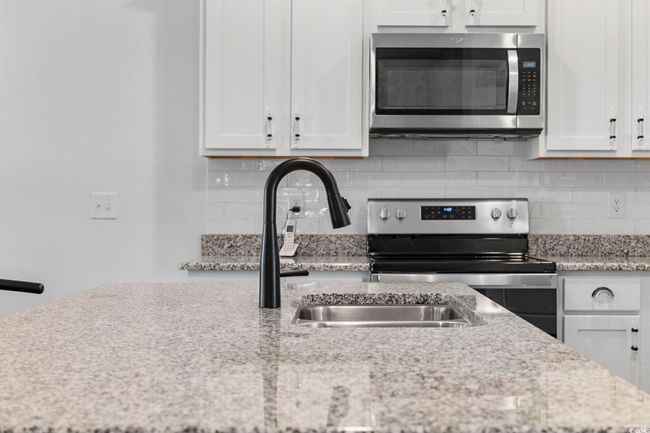 Kitchen with a sink, tasteful backsplash, white cabinets, and stainless steel appliances | Image 10