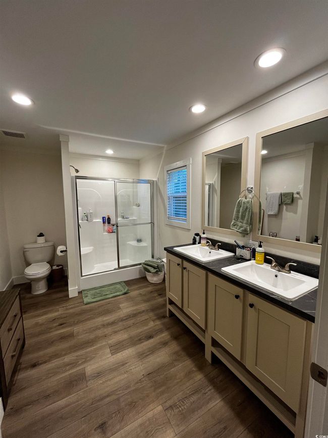 Full bath featuring a stall shower, double vanity, wood finished floors, and recessed lighting | Image 18