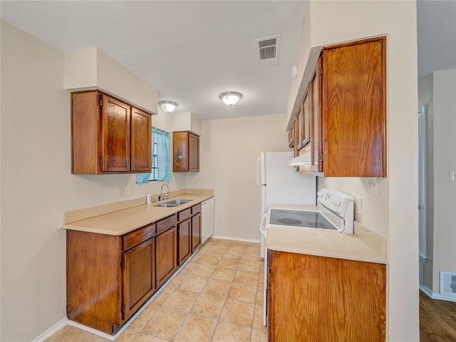 Kitchen featuring a sink, white appliances, brown cabinetry, and light countertops | Image 8