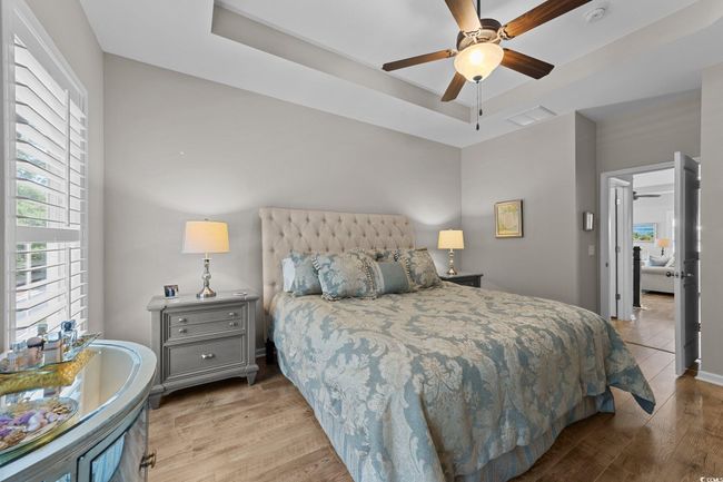 Bedroom with a tray ceiling, wood finished floors, ceiling fan, and baseboards | Image 15