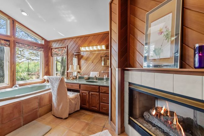 Full bathroom featuring vanity, wood walls, lofted ceiling, a garden tub, and a multi sided fireplace | Image 19