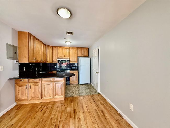 Kitchen with freestanding refrigerator, a peninsula, light wood-style flooring, and tasteful backsplash | Image 16