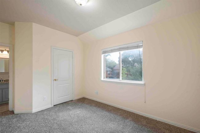 Unfurnished bedroom with baseboards, ensuite bath, carpet floors, and vaulted ceiling | Image 20