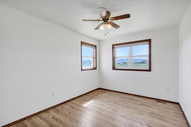 bedroom featuring baseboards, light wood finished floors, and ceiling fan | Image 38