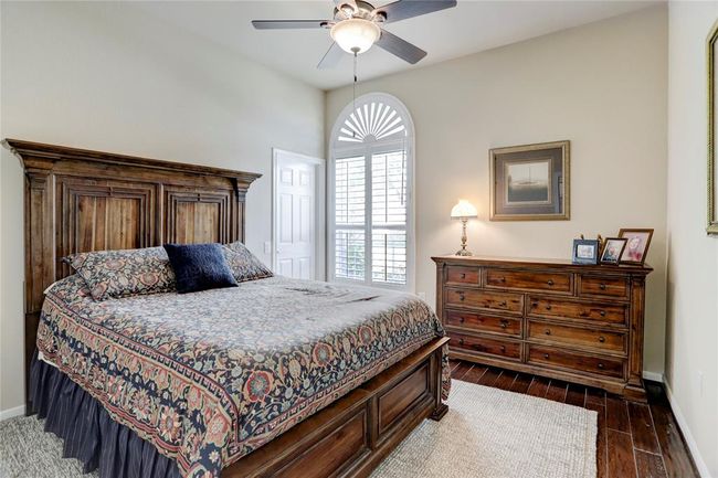 This front secondary bedroom is well-lit with engineered hardwood floors and an arched window with plantation shutters. | Image 22