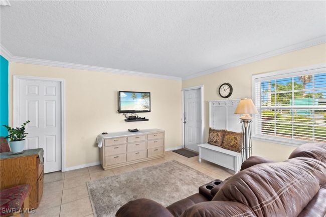 Living room with light tile patterned flooring, ornamental molding, baseboards, and a textured ceiling | Image 10