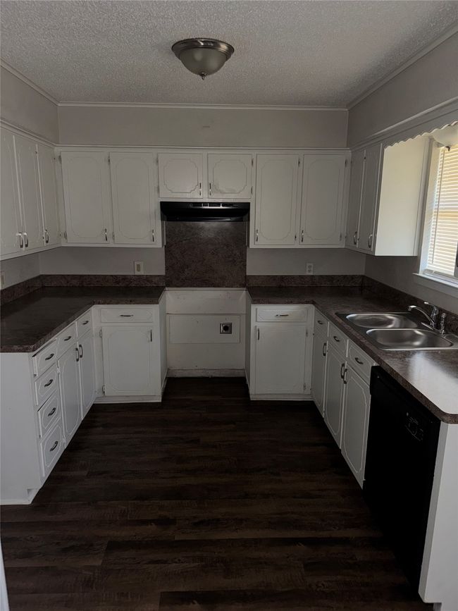 Kitchen featuring dishwasher, a textured ceiling, a sink, under cabinet range hood, and white cabinets | Image 6