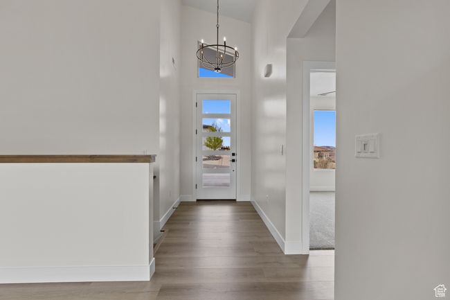Entrance foyer with baseboards, a high ceiling, wood finished floors, and an inviting chandelier | Image 26