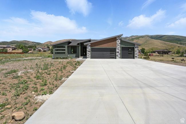 Modern home featuring a mountain view, a garage, stone siding, and driveway | Image 59
