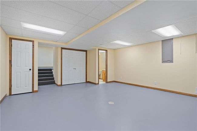 Finished below grade area featuring electric panel, a paneled ceiling, baseboards, and stairs | Image 10