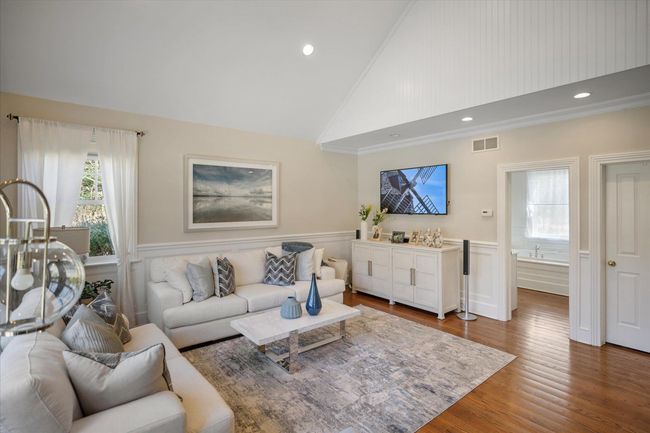 Living area with wood finished floors, ornamental molding, high vaulted ceiling, visible vents, and wainscoting | Image 20