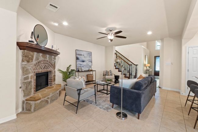Living area featuring stairs, a fireplace, a ceiling fan, light tile patterned flooring, and recessed lighting | Image 6