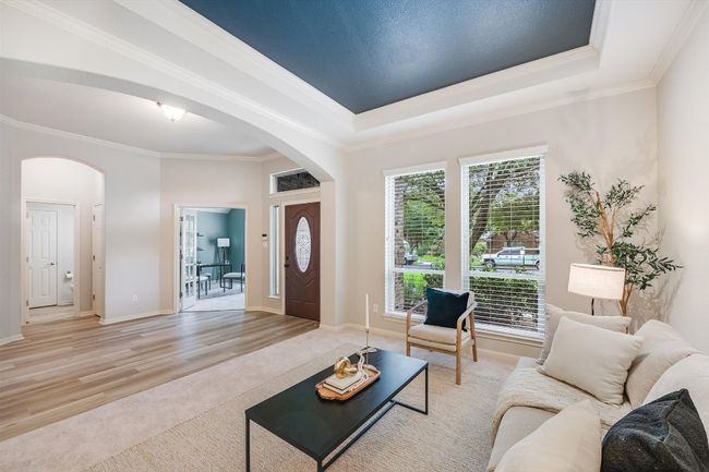 Living room featuring arched walkways, ornamental molding, light wood-type flooring, and a raised ceiling | Image 10