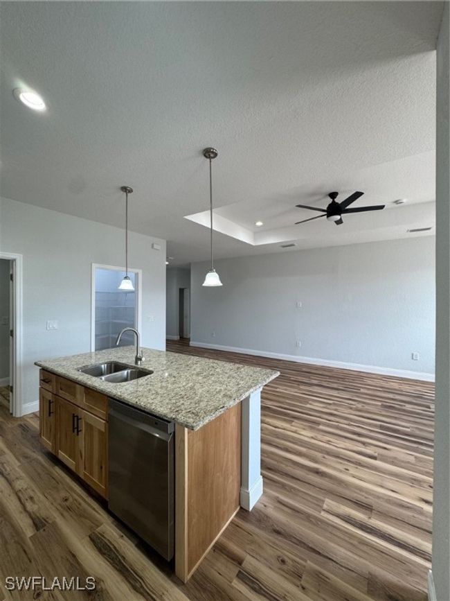 Kitchen with a sink, dishwashing machine, baseboards, an island with sink | Image 4