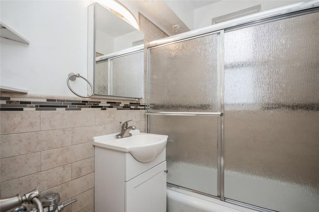 Bathroom featuring vanity, combined bath / shower with glass door, and tile walls | Image 12