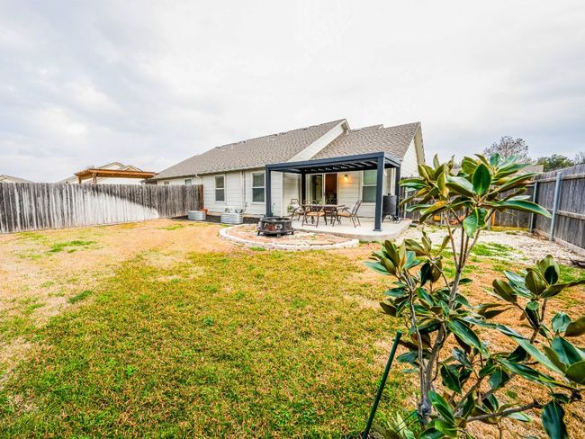 Rear view of property with roof with shingles, a yard, an outdoor fire pit, a patio area, and a fenced backyard | Image 7
