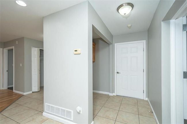 Hallway with visible vents, baseboards, and light tile patterned flooring | Image 18