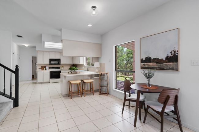 Kitchen featuring a peninsula, visible vents, black microwave, range with electric stovetop, and light countertops | Image 11