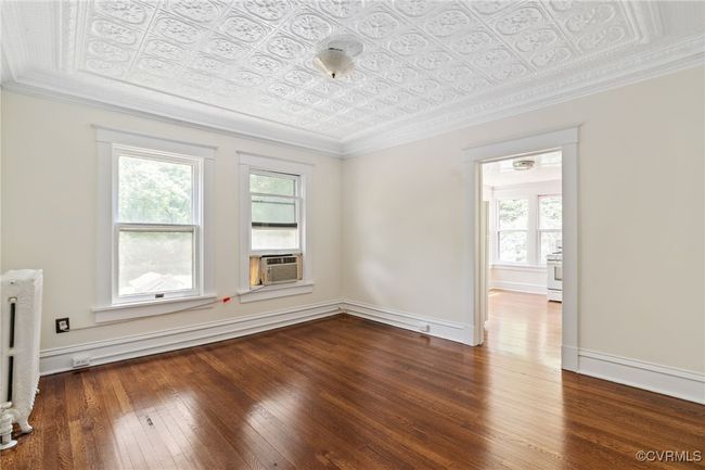 Unfurnished living room featuring an ornate ceiling, healthy amount of natural light, wood-type flooring, cooling unit, and radiator heating unit | Image 37