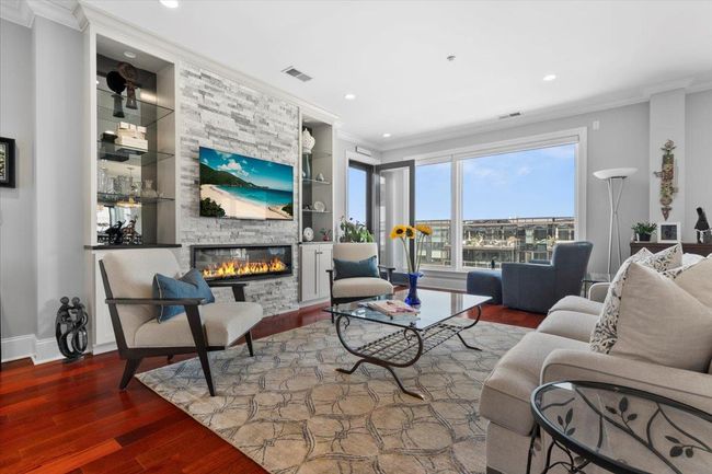 Living room featuring visible vents, built in features, a large fireplace, wood finished floors, and baseboards | Image 7